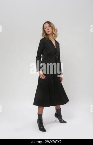 Serie von Studiofotos von weiblichem Model mit schwarzem Blazer und schwarzem Midikleid Stockfoto