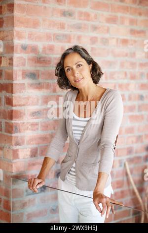 Glastor, Porträt und Haus mit Seniorin, Mode und Inneneinrichtung mit selbstbewusster Dame. Gesicht, reife Person und Rentner mit stilvoll Stockfoto