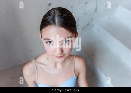 Junge Ballerina Nahaufnahme ausdrucksstarkes Porträt. Die Balletttänzer stehen im Gesicht und blicken mit subtilem Selbstbewusstsein vor strukturiertem Hintergrund. Kopieren Stockfoto