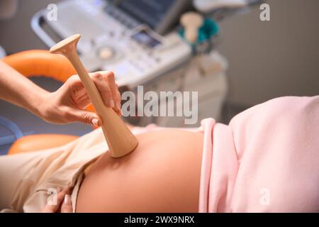 Unerkennbarer Arzt untersucht schwangere Frau, die auf den Herzschlag des Babys hört Stockfoto