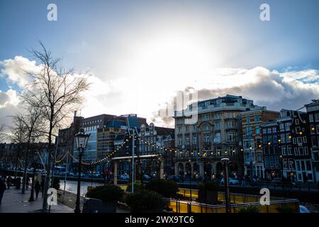 Erkunden Sie den Charme und das architektonische Erbe Amsterdams durch seine lebhaften Straßen, wo ikonische Gebäude ein malerisches Stadtbild prägen. Stockfoto