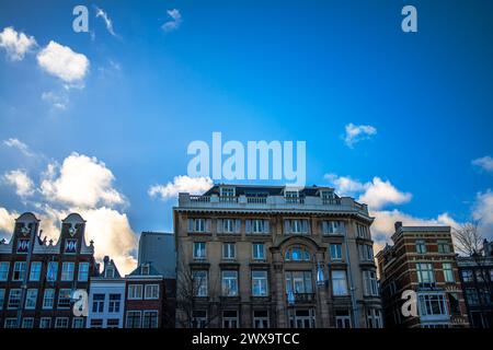 Erkunden Sie den Charme und das architektonische Erbe Amsterdams durch seine lebhaften Straßen, wo ikonische Gebäude ein malerisches Stadtbild prägen. Stockfoto