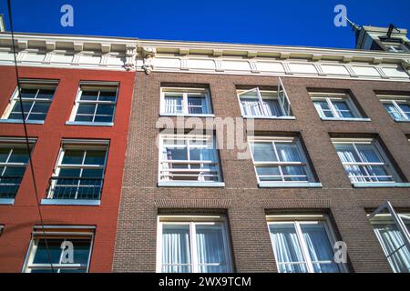 Erkunden Sie den Charme und das architektonische Erbe Amsterdams durch seine lebhaften Straßen, wo ikonische Gebäude ein malerisches Stadtbild prägen. Stockfoto