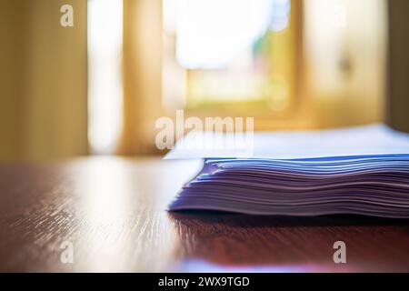 Ein makelloser Schreibtisch mit ordentlich gestapelten weißen A4-Papieren schafft einen organisierten und effizienten Arbeitsplatz für professionelle Zwecke. Stockfoto