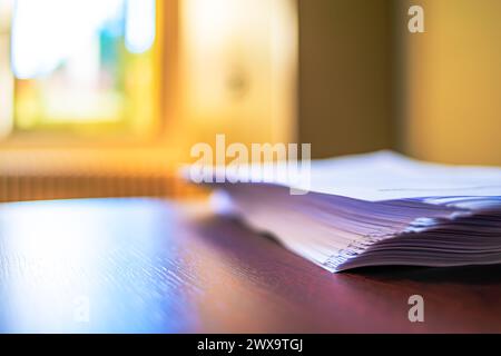 Ein makelloser Schreibtisch mit ordentlich gestapelten weißen A4-Papieren schafft einen organisierten und effizienten Arbeitsplatz für professionelle Zwecke. Stockfoto