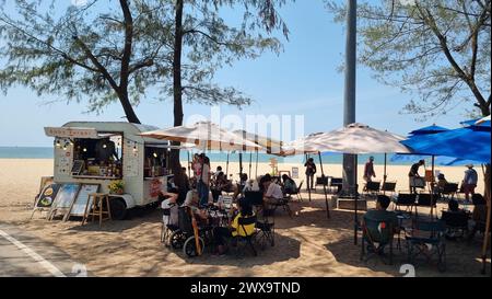 Rayong Thailand 13 März 2024, Eine Gruppe von Menschen, die sich unter bunten Sonnenschirmen an einem Sandstrand entspannen und die warme Sonne und den malerischen Blick auf das Meer genießen. Stockfoto