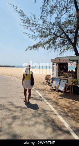 Rayong Thailand 13. März 2024, Ein stilvoller Mann, der eine geschäftige Straße entlang läuft, gesäumt von Essenswagen, und die Sehenswürdigkeiten und Gerüche von Street Food-Anbietern genießt. Stockfoto