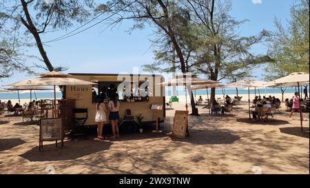 Rayong Thailand 13 März 2024, Eine vielfältige Gruppe von Menschen, die frisch zubereitete Speisen aus einem hellen Food Truck an einem sonnigen Strand genießen. Stockfoto