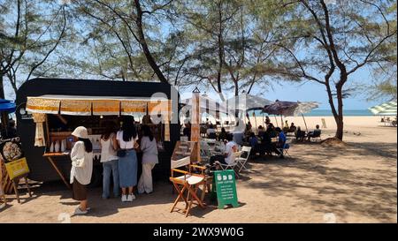 Rayong Thailand 13. März 2024, Eine Gruppe von Menschen steht zusammen am Sandstrand, jeder hält einen bunten Regenschirm über ihren Köpfen, um vor der Sonne zu schützen. Stockfoto