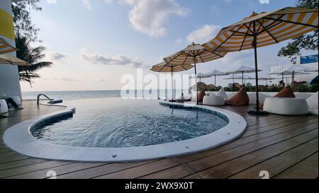 Bangsaray Pattaya Thailand 28 Februar 2024, Ein glitzernder, großer Swimmingpool, umgeben von bunten Sonnenschirmen und einladenden Stühlen, schafft eine friedliche und entspannende Umgebung unter der Sonne. Stockfoto