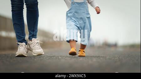 Das Nahbein eines Säuglings, das mit der Mutter auf einem Weg geht Stockfoto