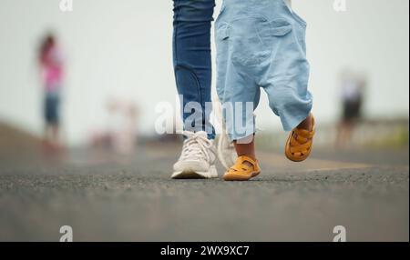 Das Nahbein eines Säuglings, das mit der Mutter auf einem Weg geht Stockfoto