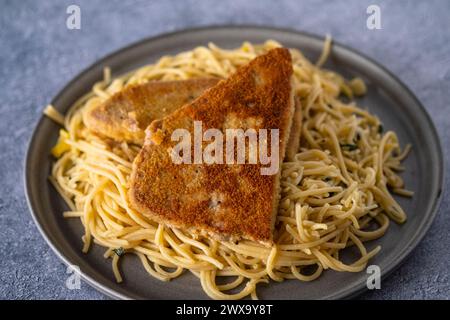 Panierte Thunfischsteaks mit Spaghetti aglio i olio Stockfoto