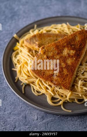 Panierte Thunfischsteaks mit Spaghetti aglio i olio Stockfoto