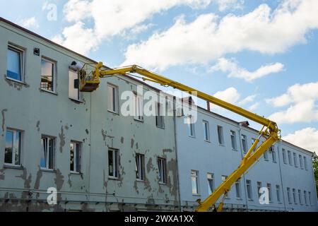 Arbeiter im Korb eines Lifts reparieren die Fassade des Verwaltungsgebäudes. Arbeiter in der hydraulischen Heberampe reparieren die Fensteröffnung. Bu Stockfoto