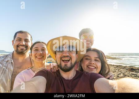 Eine Gruppe von Latino-Freunden, die ein Selfie machen, während sie einen sonnigen Tag am Strand genießen Stockfoto