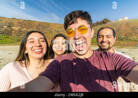 Eine Gruppe von Latino-Freunden, die ein Selfie machen, während sie einen sonnigen Tag am Strand genießen Stockfoto