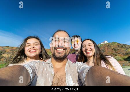 Eine Gruppe von Latino-Freunden, die ein Selfie machen, während sie einen sonnigen Tag am Strand genießen Stockfoto