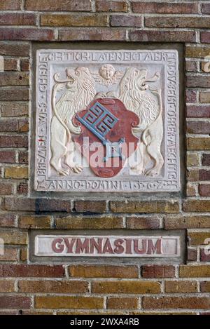 Ein sogenannter Wappenstein und ein Gymnasium-Schriftzug an einer Außenmauer der Oberschule am Leibnizplatz in Bremen, einem ehemaligen Gymnasium, das mittlerweile eine Gesamtschule ist. Der Wappenstein ist eine von mehreren Nachbildungen des Originals, das 1562 am damaligen Bremer Herdentor angebracht wurde. Die niederdeutsche Inschrift am Rand lautet: Bremen wes ghedechtich / late neict mer in / du beist ohrer mechtich / Anno Domini 1562 - Wörtliche Übersetzung laut Stadthistoriker Peter Strotmann: Bremen sei bedächtig, lass nicht mehr ein, du seiest ihrer mächtig. Anno Domini 1562. - Sinngemä Stockfoto