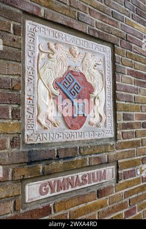 Ein sogenannter Wappenstein und ein Gymnasium-Schriftzug an einer Außenmauer der Oberschule am Leibnizplatz in Bremen, einem ehemaligen Gymnasium, das mittlerweile eine Gesamtschule ist. Der Wappenstein ist eine von mehreren Nachbildungen des Originals, das 1562 am damaligen Bremer Herdentor angebracht wurde. Die niederdeutsche Inschrift am Rand lautet: Bremen wes ghedechtich / late neict mer in / du beist ohrer mechtich / Anno Domini 1562 - Wörtliche Übersetzung laut Stadthistoriker Peter Strotmann: Bremen sei bedächtig, lass nicht mehr ein, du seiest ihrer mächtig. Anno Domini 1562. - Sinngemä Stockfoto