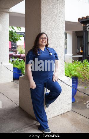Junge Krankenschwester mit blauen Peelings, die draußen stehen Stockfoto