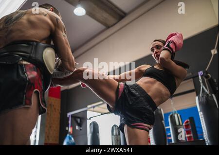 Kampfkünstlerin, die Tritttechniken mit Trainer übt Stockfoto