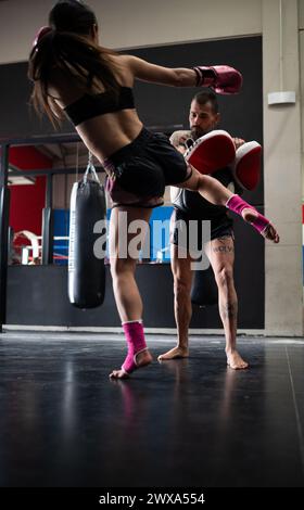 Eine Kämpferin übt Muay Thai mit Trainer im Boxclub Stockfoto