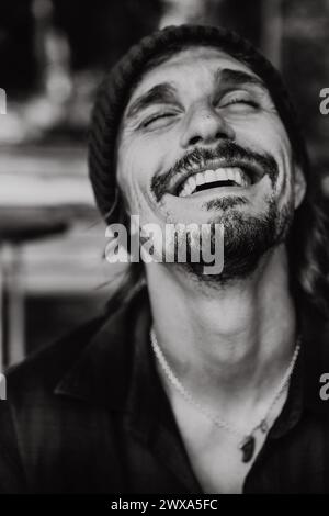 Schwarz-weiß-Porträt des lachenden Mannes. Nahaufnahme, ausdrucksstarke Augen. Stockfoto