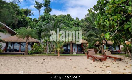 Zwei Liegestühle an einem Sandstrand mit Blick auf die ruhigen Meereswellen unter einem klaren blauen Himmel an einem sonnigen Tag. Koh Kradan Thailand Stockfoto