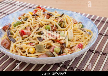 Traditionelle gelbe chinesische Nudeln mit Gemüse, Fleisch und Pilzen. Selektiver Fokus mit geringer Schärfentiefe. Stockfoto