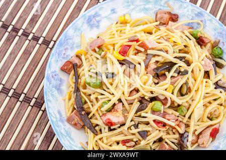 Traditionelle gelbe chinesische Nudeln mit Gemüse, Fleisch und Pilzen. Selektiver Fokus mit geringer Schärfentiefe. Stockfoto