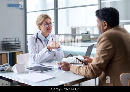 Porträt einer lächelnden Ärztin, die mit dem Patienten in der Klinik spricht und den Kopierraum genießt Stockfoto