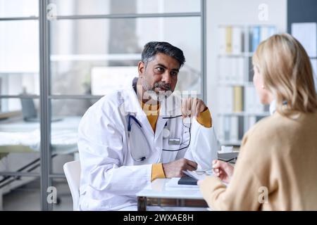 Porträt einer aufmerksamen Nahost-Ärztin, die während der Sprechstunde im klinischen Kopierraum eine Patientin hört Stockfoto