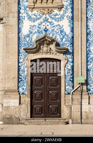 Eine Tür vor der blau-weiß gekachelten Fassade der Kirche Igreja do Carmo in Porto, Portugal Stockfoto