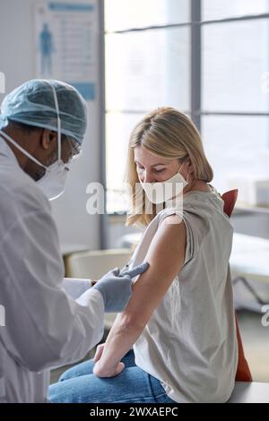 Vertikalporträt einer Reifen Frau, die in Klinik und Maske geimpft wird Stockfoto