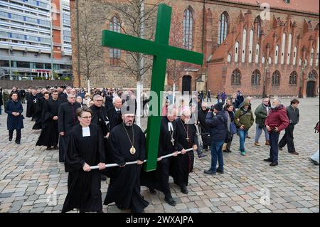 Die großen christlichen Kirchen begehen am 29.03.2024 wieder eine Karfreitagsprozession durch Berlins Mitte. Sie sollen an den Leidensweg Christi erinnern. An der Spitze des Zuges wird traditionell ein rund 50 Kilogramm schweres Kreuz getragen. Die oekumenische Prozession beginnt im Anschluss an einen Gottesdienst in der Marienkirche im Bild am Alexanderplatz. Von dort fuehrt sie zum Berliner Dom, ueber die Straße unter den Linden zur Neuen Wache und endet auf dem Bebelplatz vor der Hedwigs-Kathedrale. Im Bild vlnr.: Superintendentin Silke Radosh-hinder, Bischof Emmanuel von Christoupolis, Erz Stockfoto