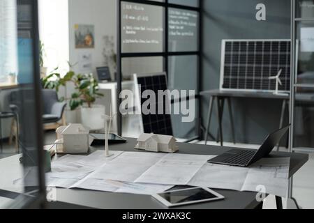Entwurf mit Skizzen umgeben von digitalen Tablets, Laptop und Modellen von Häusern und Windmühle am Arbeitsplatz eines modernen Architekten im Büro Stockfoto
