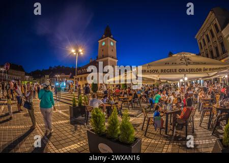 BRASOV, RUMÄNIEN - 11. JULI 2020: Nächtlicher Blick auf den Ratsplatz mit Touristen, im historischen Zentrum der Stadt. Es ist umgeben von 18. Stockfoto