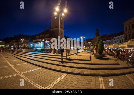 BRASOV, RUMÄNIEN - 11. JULI 2020: Nächtlicher Blick auf den Ratsplatz mit Touristen, im historischen Zentrum der Stadt. Es ist umgeben von 18. Stockfoto