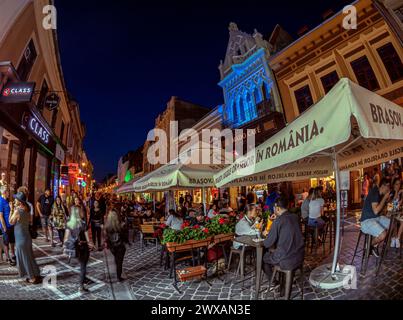 BRASOV, TRANSSILVANIEN, RUMÄNIEN - 12. JULI 2020: Nachtblick mit kleinen Geschäften und Terrassen auf der malerischen Straße Republicii, in der Historica Stockfoto