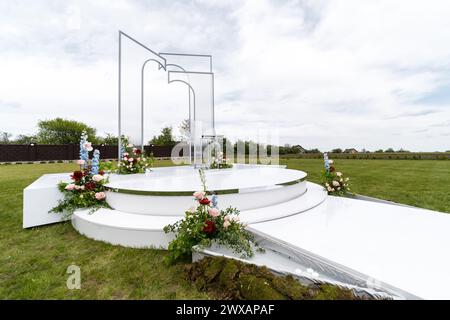 Eine große weiße Skulptur steht in der Mitte eines lebendigen grünen Feldes unter freiem Himmel. Stockfoto