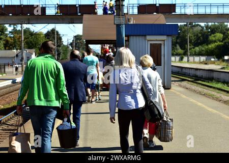 Eine Gruppe von Passagieren mit Gepäck in der Hand geht entlang des Bahnsteigs. Hochwertiges Foto Stockfoto