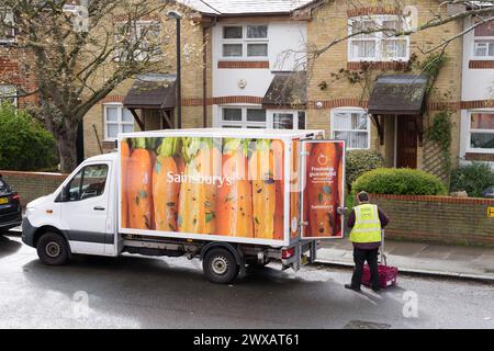 Der Fahrer bereitet die Kiste für die Lieferung nach Hause vor einer Wohnterrasse in London, England, Großbritannien vor Stockfoto