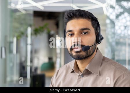 Konzentrierter Kundendienstmitarbeiter mit Headset, das in einer hellen, modernen Büroumgebung arbeitet. Stockfoto