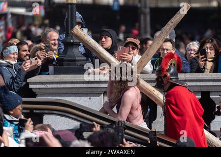 Trafalgar Square, London, Großbritannien. März 2024. Am Karfreitag am Osterabend präsentierte die Theaterbesetzung von Wintershall „die Passion Jesu“, ein Stück, das die Bibelgeschichte Christi durch die „Wunder“, das letzte Abendmahl, und die Kreuzigung durch die Römer, bevor sie wieder zur Auferstehung aufstehen, alle benutzten den Trafalgar Square als Bühne für dieses kostenlose öffentliche Ereignis. Eine große Menschenmenge von Tausenden, die auf den Platz gepackt sind, beobachtete, wie Christus vom Schauspieler Peter Bergin dargestellt wird, der hier das Kreuz trägt Stockfoto