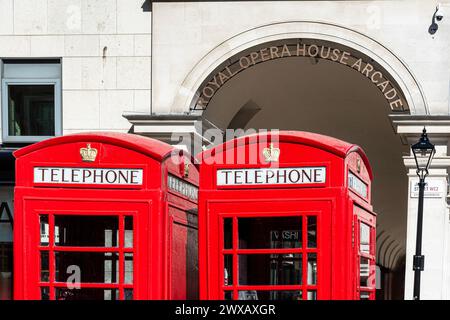 Rote Telefonzellen vor dem Eingang zur Royal Opera House Arcade mit dem Eingangsschild Covent Garden, London in der Sonne. Stockfoto