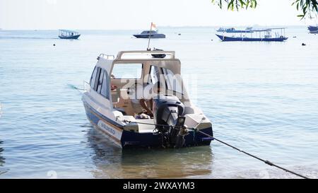 Ein weißes Schnellboot eines Lombok-Einwohners, der sich am Strand lehnt. Dieses Boot wird benutzt, um zu den Gili Inseln zu überqueren Stockfoto