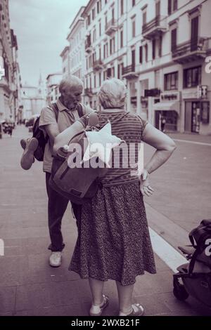 Ein älteres Ehepaar reist durch Europa. Großvater und Großmutter mit Rucksäcken spazieren durch die Stadt in Italien. Alte Leute reisen gerne. Stockfoto