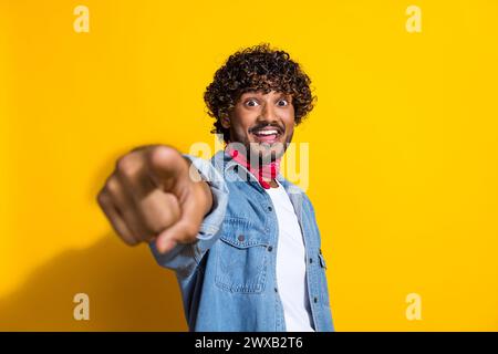 Foto-Porträt des netten jungen männlichen Punktes, den Sie wählen, aufgeregtes Tragen trendiges Denim-Outfit roter Schal isoliert auf gelbem Hintergrund Stockfoto