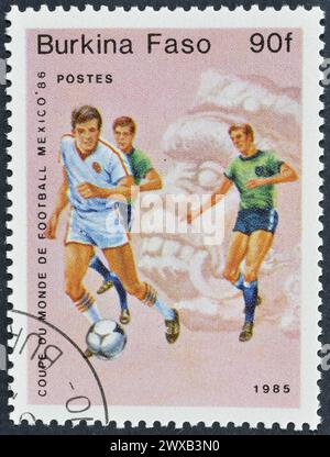 Von Burkina Faso gedruckte Briefmarke, auf der Fußballspieler, FIFA Fussball-Weltmeisterschaft 1986 - Mexiko, um 1985 gezeigt werden. Stockfoto